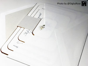Stack invitations in a cotton envelope tagged