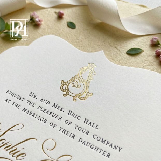 Close-up of gold foil crest and letterpress typography on die cut wedding invitation