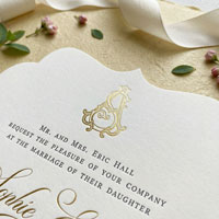 Close-up of gold foil crest and letterpress typography on die cut wedding invitation