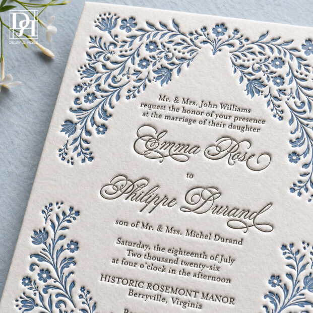 Close-up of blue floral letterpress border and elegant gray typography on luxury cotton wedding invitation.