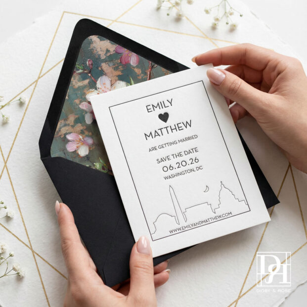 Custom Washington DC save the date card held in hands with black envelope